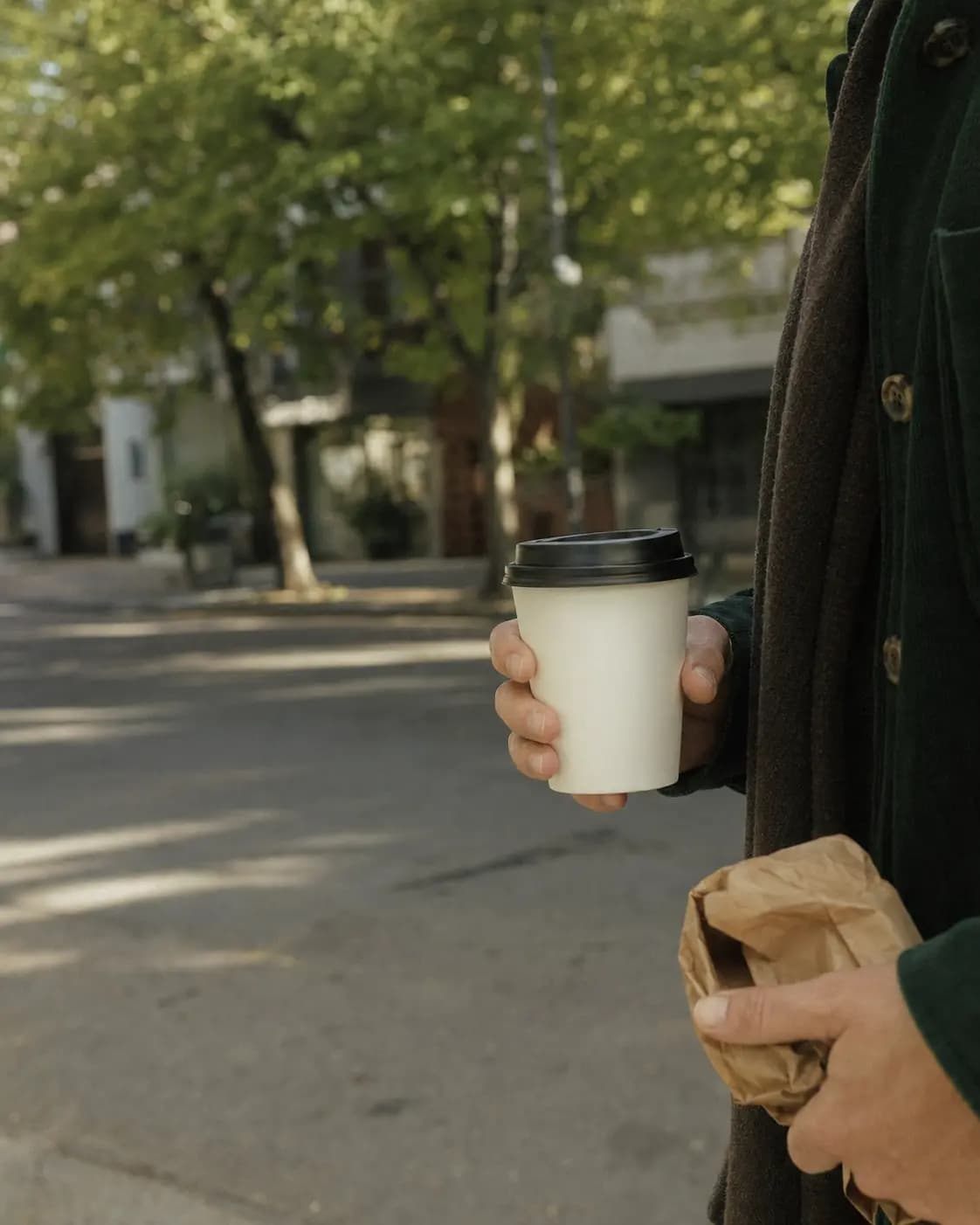Una persona lleva su café por las calles de Martínez